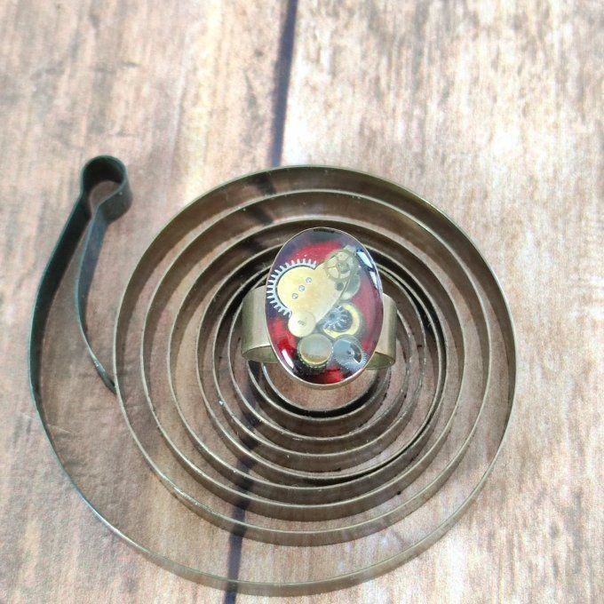 Bague ovale rouge avec des pièces d'horlogerie  
