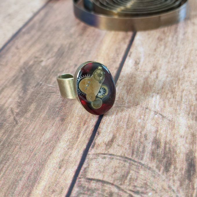 Bague ovale rouge avec des pièces d'horlogerie  