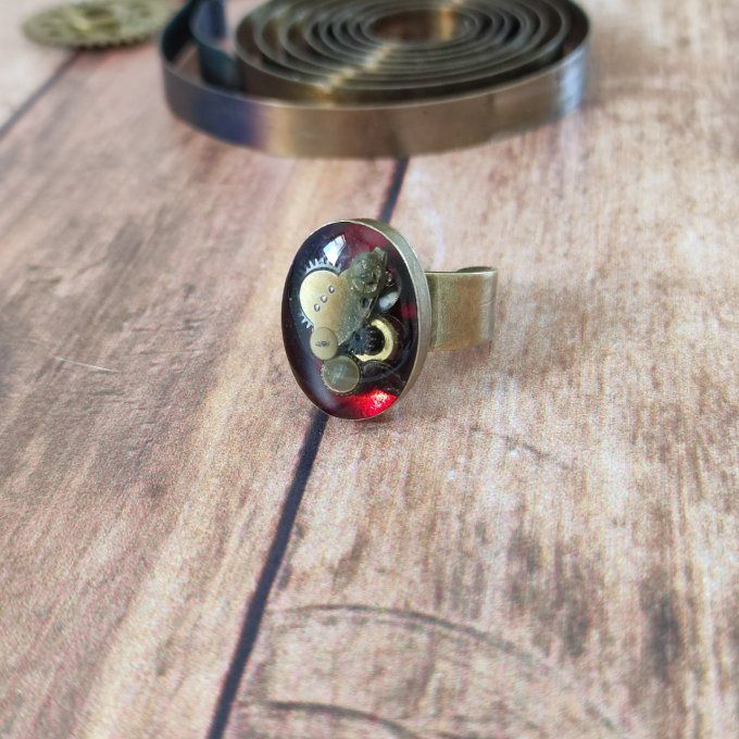 Bague ovale rouge avec des pièces d'horlogerie  
